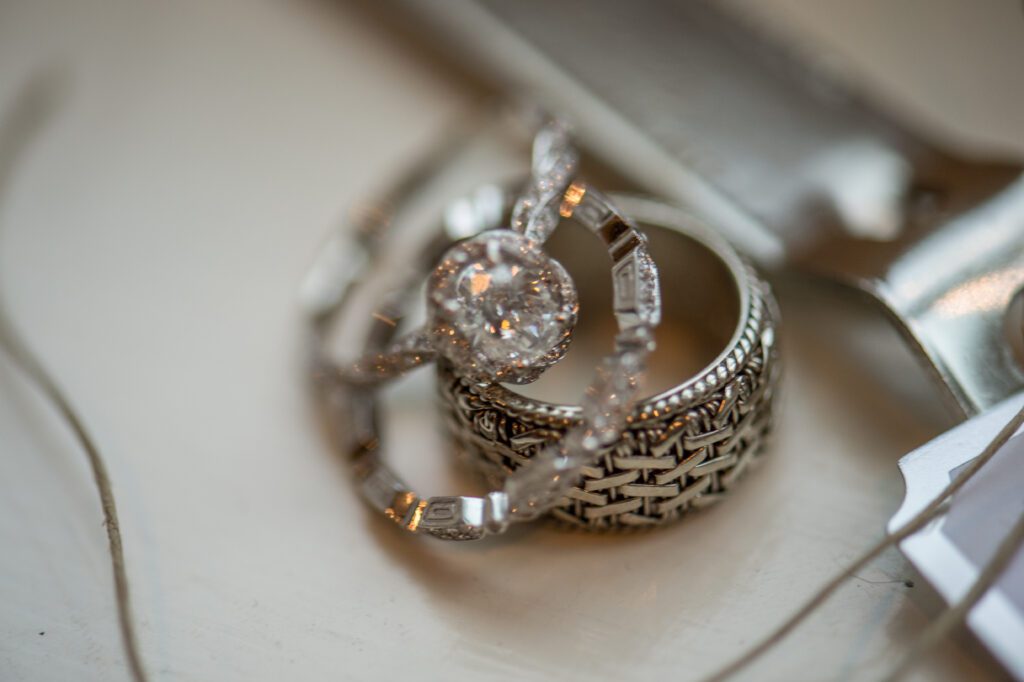 three wedding rings sit together with the lost mens braided basket weave wedding band on the bottom