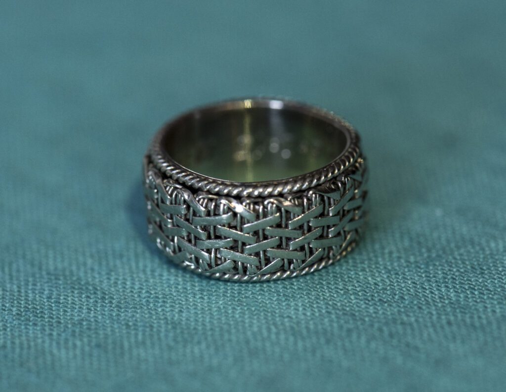 Lost mens braided basket weave wedding band on turquoise cloth.