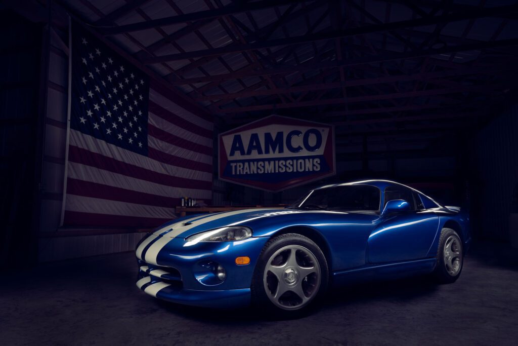 A three quarter shot of a dodge viper in front of a large American Flag and AAMCO Transmission sign in a shed. Columbia Missouri Car Photography.