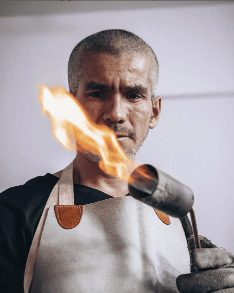 Elier Olivos holds a torch in his jewelry workshop in Peru.