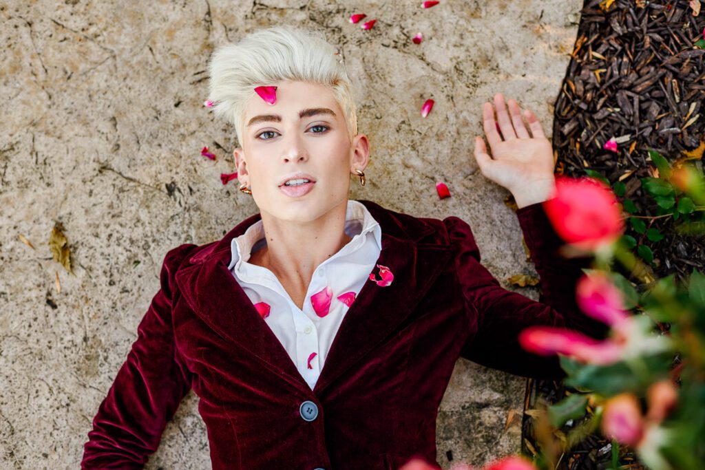 senior covered in rose petals lays on concrete shelter gardens