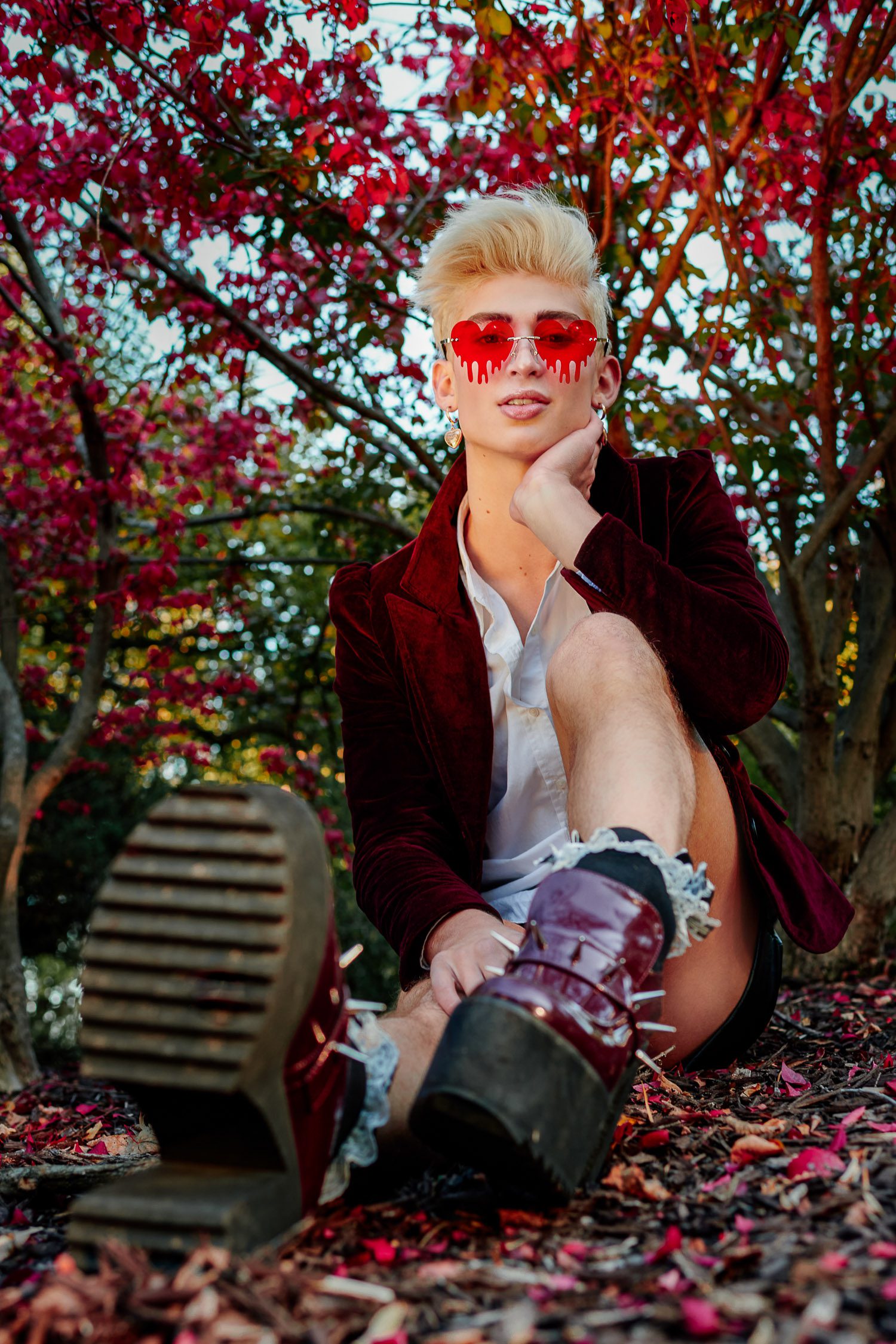 senior zachary willmore wearing red bleeding heart glasses sits in red fall leaves columbia missouri