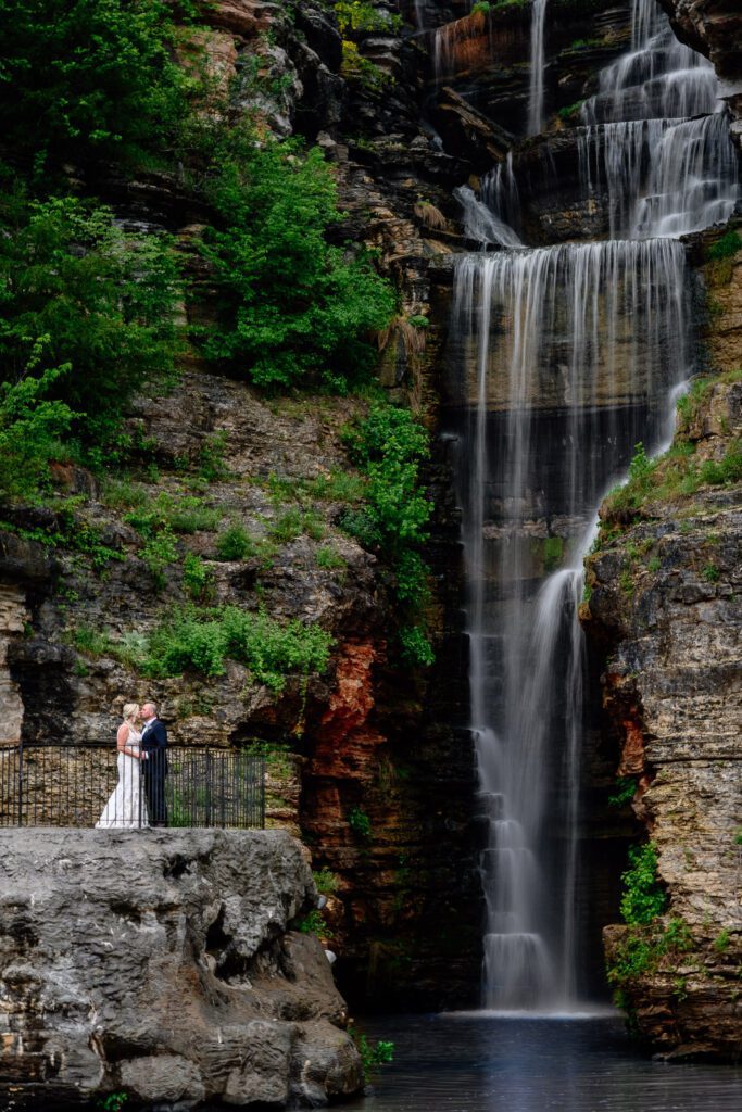 Newlywed Bride and Groom stand near Indian Cliff Falls at Dogwood Canyon near Branson, Missouri.