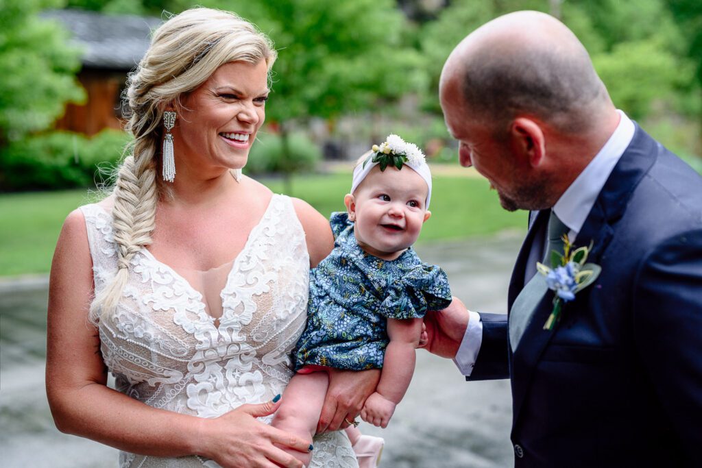 Groom talks to baby daughter as bride smiles
