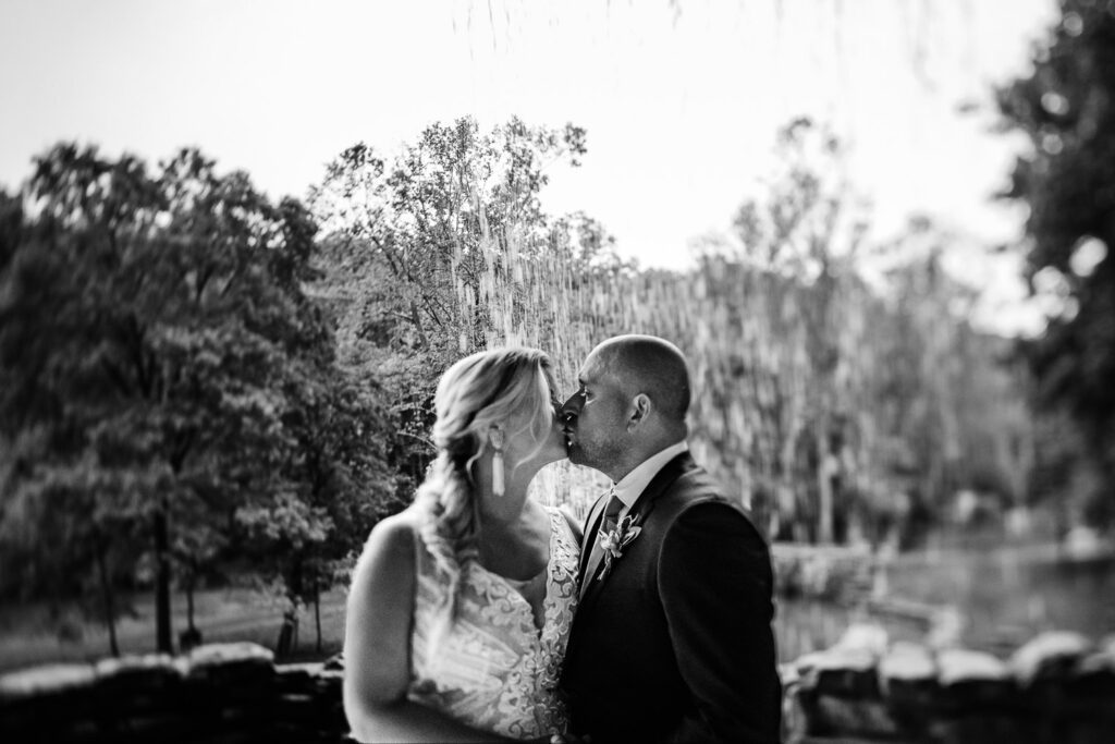 Bride and Groom kiss Black and white tilt shift photo under Great Spirt Falls Dogwood Canyon Schaefer Photography