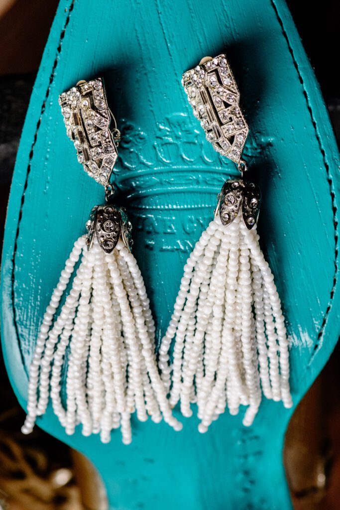 Two earrings with white beads on sole of blue boot.