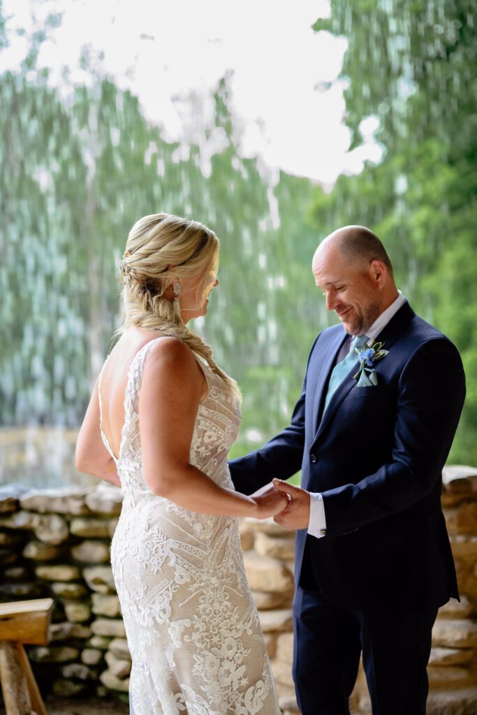 Groom sees bride in wedding dress in front of great spirit fall at Dogwood Canyon