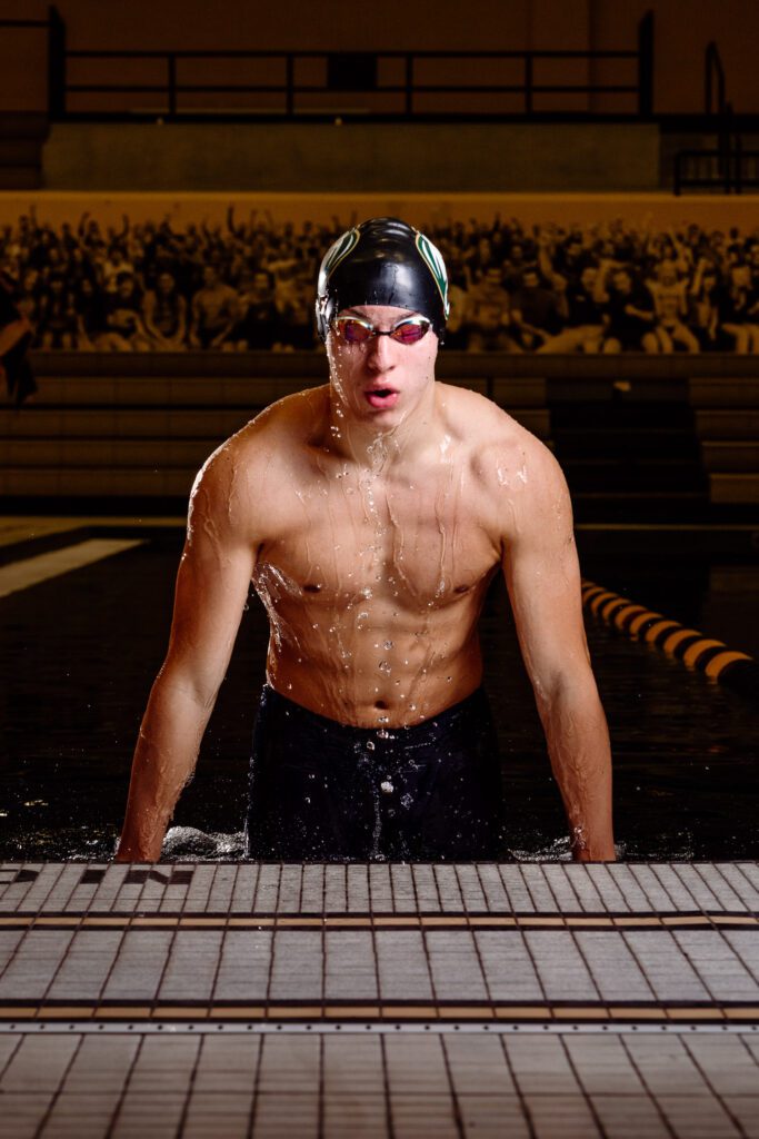 Senior guy wearing swim cap and trunks comes out of the water.