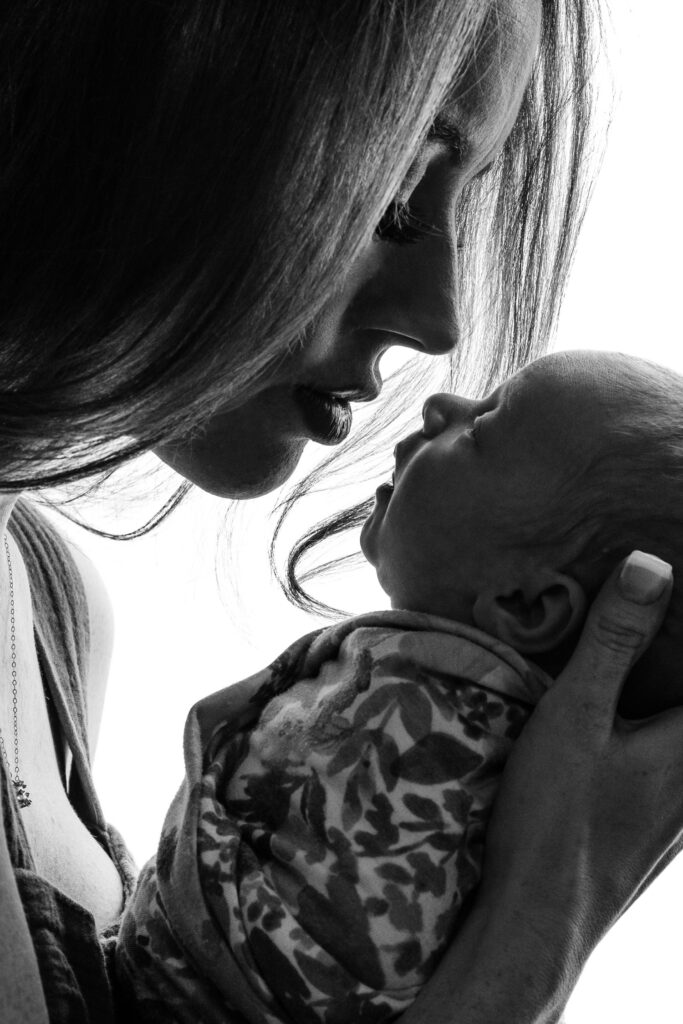 Mother with long hair and eye lashes about to kiss newborn baby