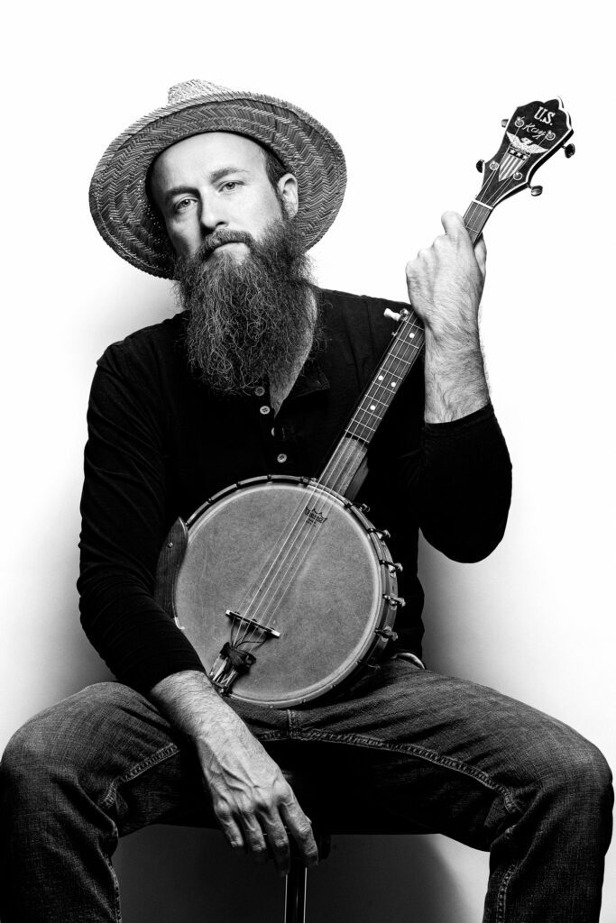 Pat Kay from the Kay Brothers Band holding a banjo on his lap.