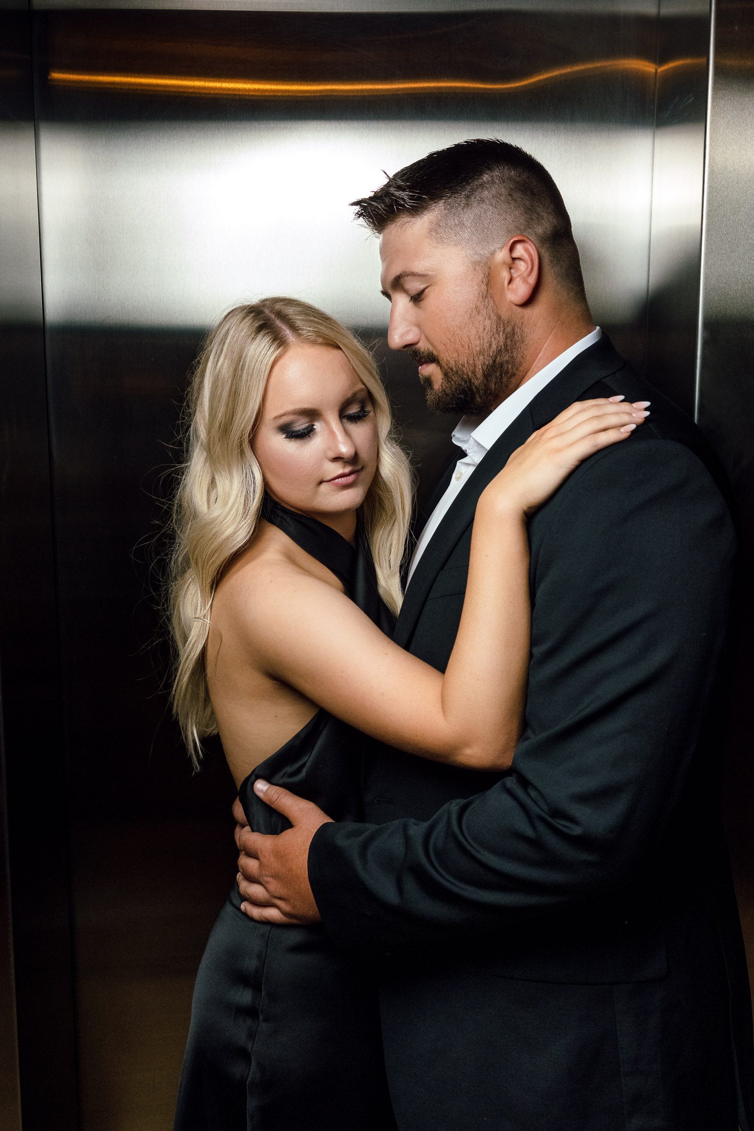 Blonde Girl and guy with beard cuddle together in elevator during engagement session

