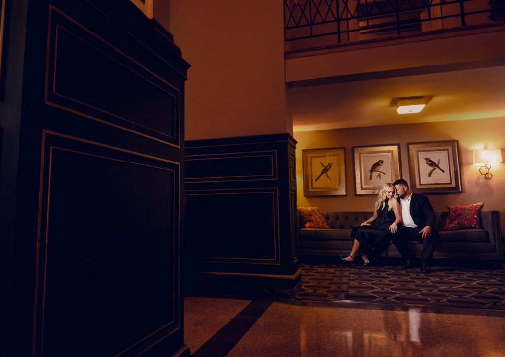 Couple sitting on couch snuggling during tiger hotel engagement session.