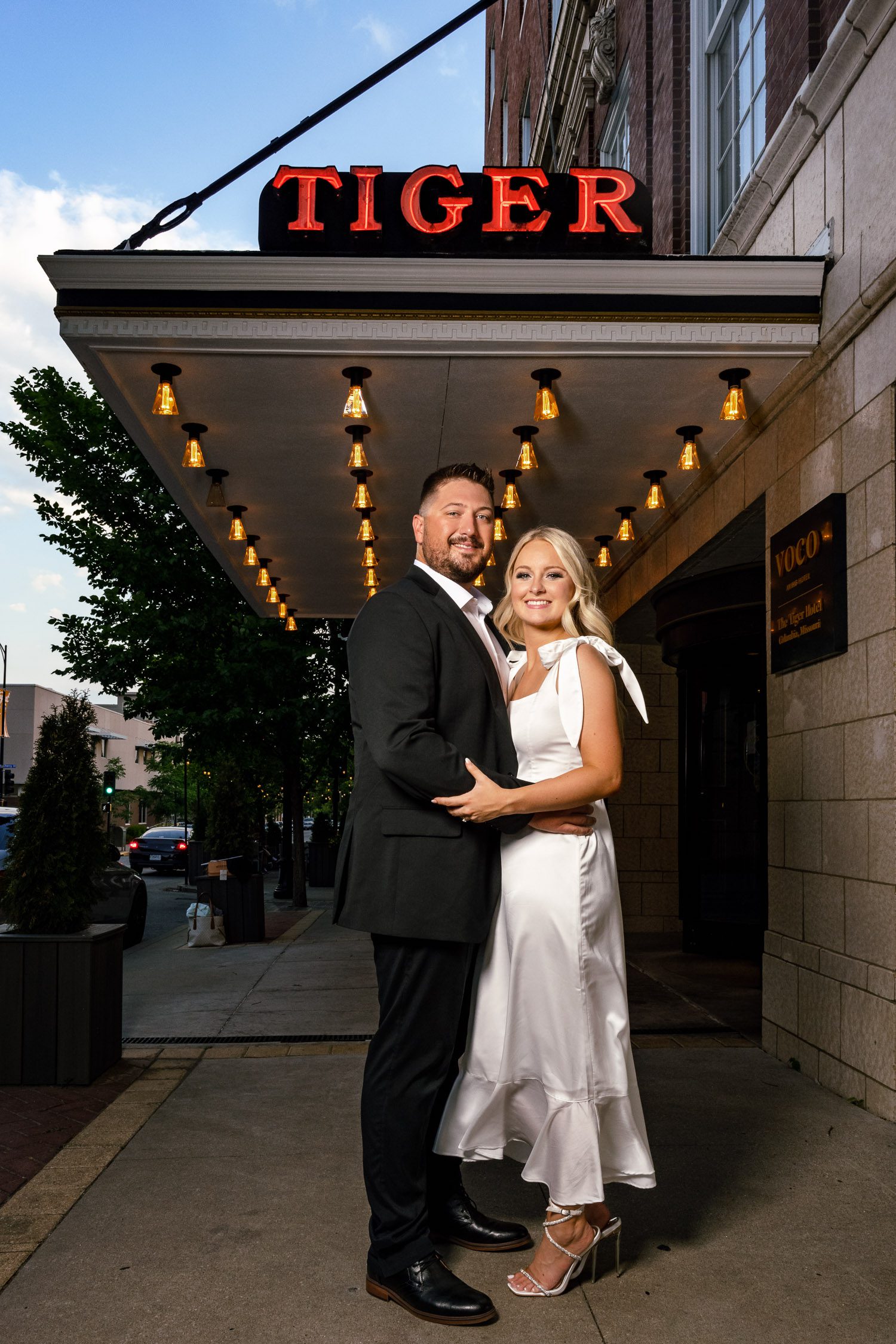 Couple pose under Tiger Hotel Neon Sign in Columbia, Missouri.