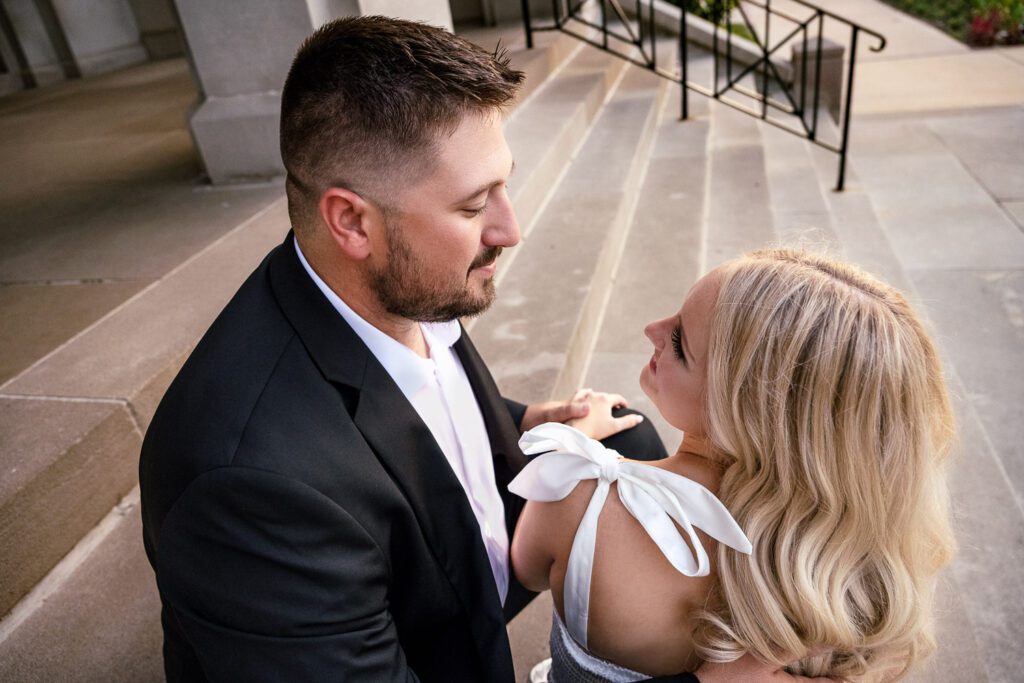 Couple sit on steps and look at each other.