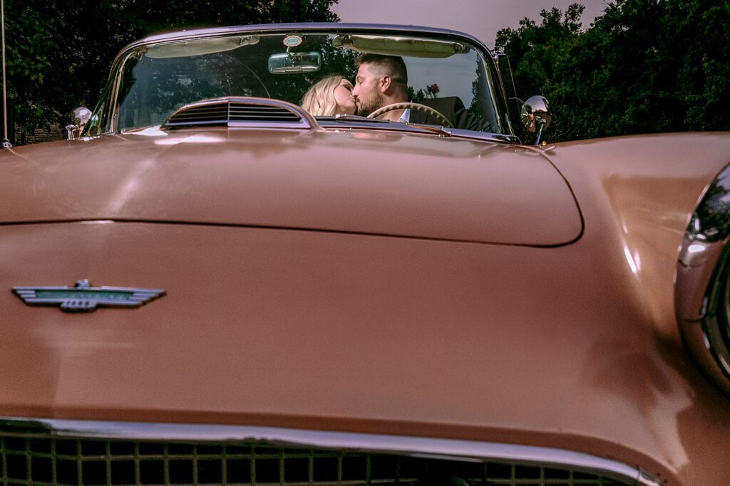 Couple kiss in buckskin colored thunderbird that was Unexpected Engagement Session Surprise