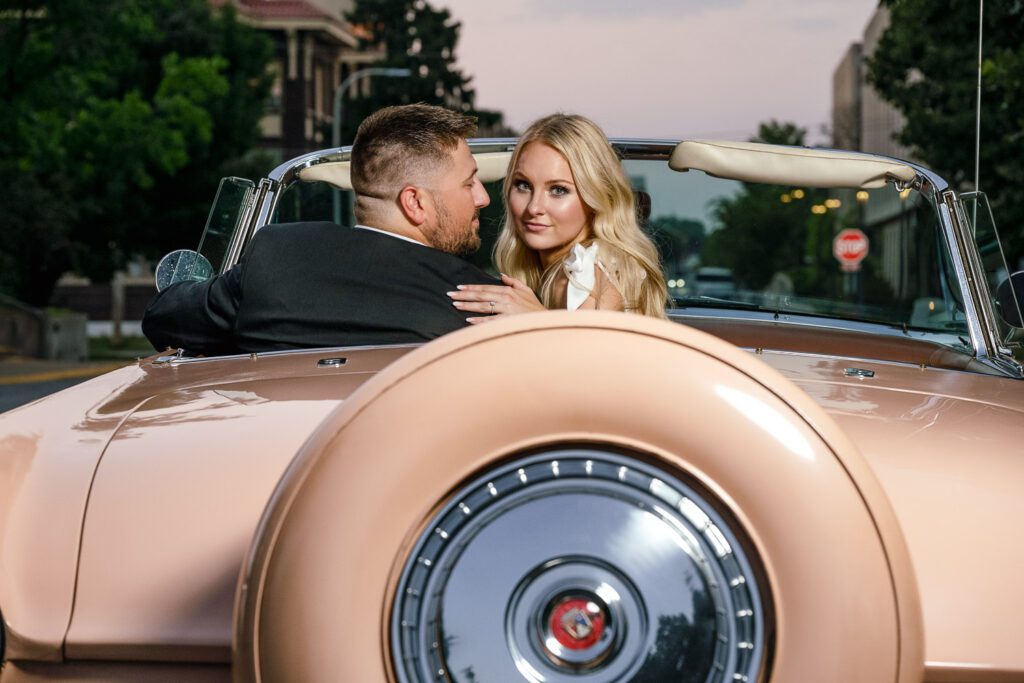 Guy and girl sit in 1956 Thunderbird as girl looks at camera during engagement session by Schaefer Photography. Unexpected Engagement Session Surprise