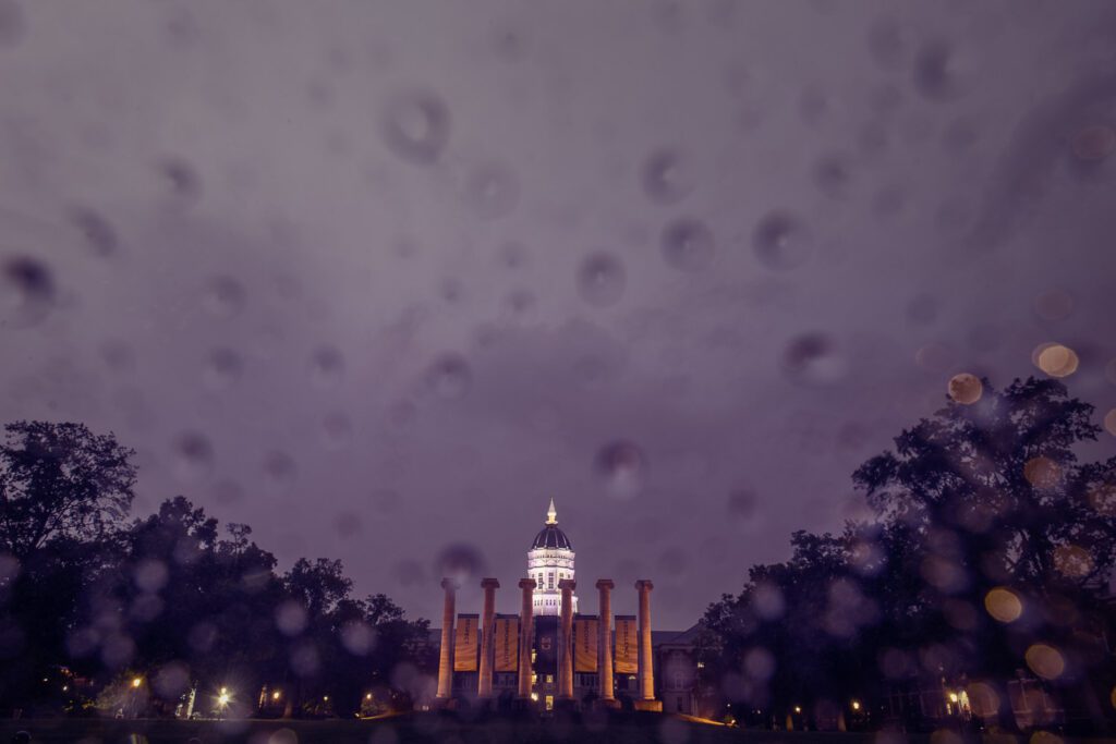 Raindrops on glass with the scenic view of Jesse Hall and the Mizzou Columns with Banners hanging between.