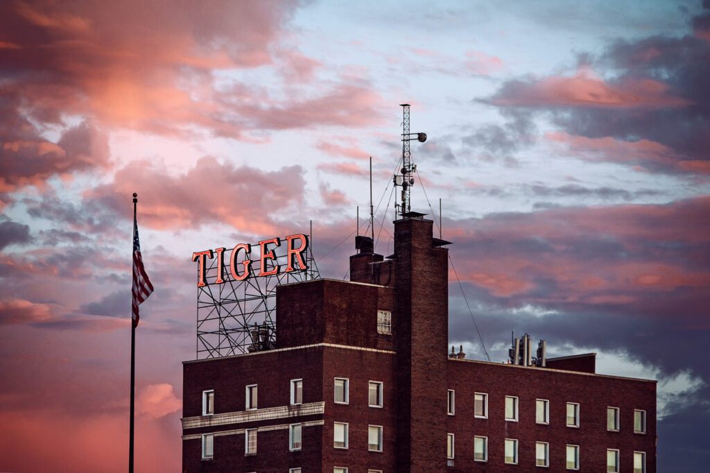 A pink and blue sunset over the Tiger Hotel with a neon Tiger sing and American Flag.