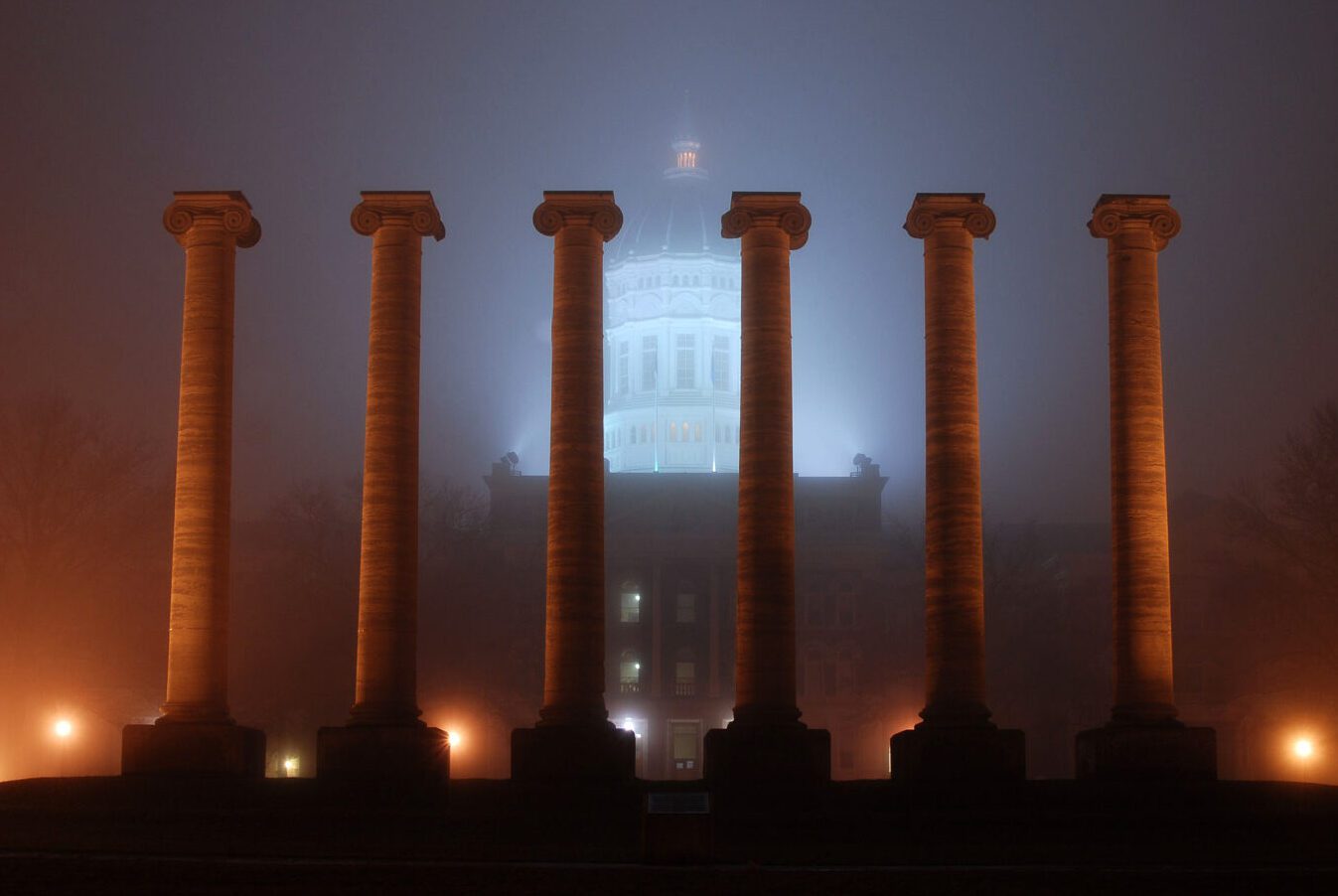Six Columns stand in front of white dome of Jesse Hall under fog.