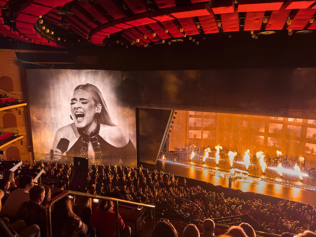Adele singing Fire and Rain during show at the Colosseum at Caesars Palace in Las Vegas by Schaefer Photography. Rain is falling on stage and fire columns shooting up.