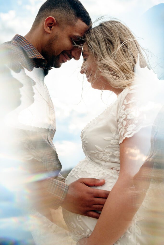 Guy looks at woman's baby bump as they touch foreheads. In Camera effects.