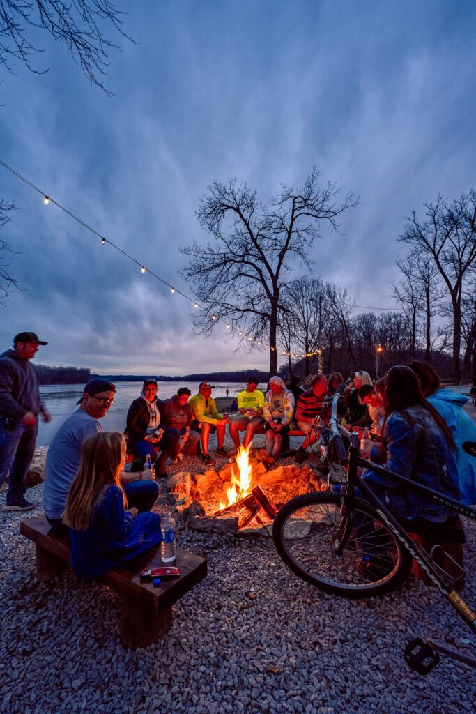 Crowd gathers around fire along the Missouri River at Cooper's Landing Marina.