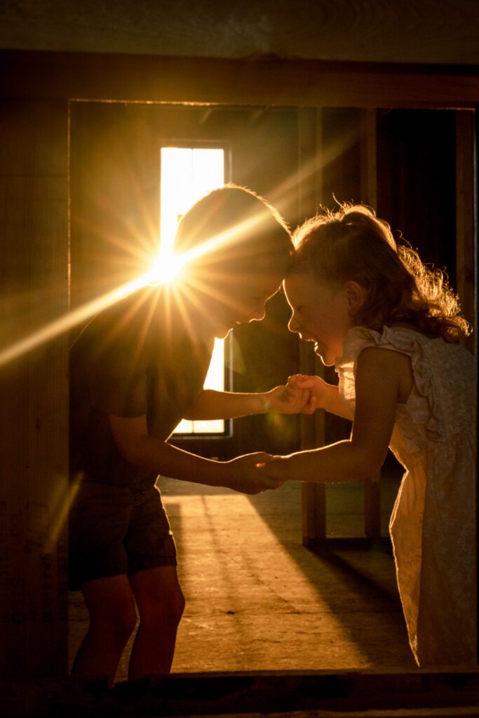 Two kids play together with sun falling on them.