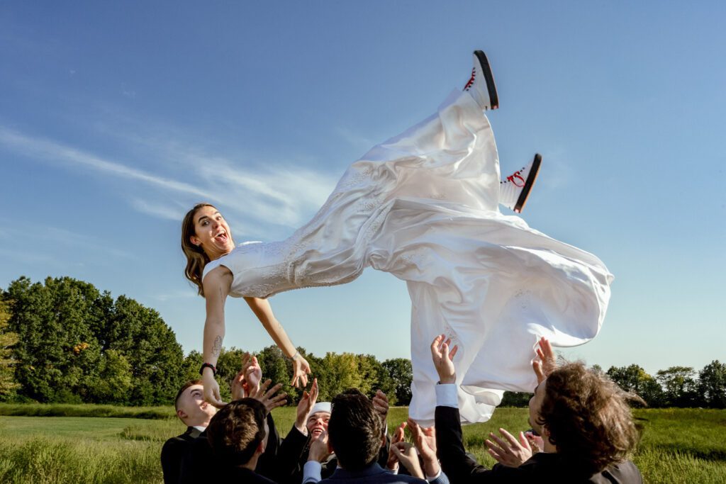 Groomsmen toss bride in the air at Emerson Fields.