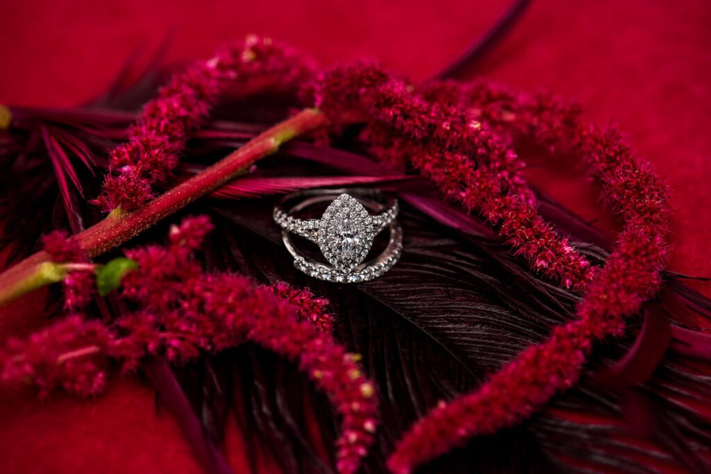 marquis wedding ring on feather with red amaranth flowers