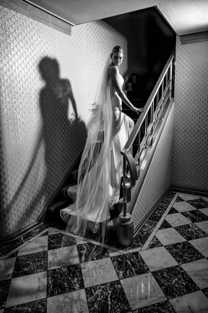 bride with flowing veil on stair case with checkered marble floors