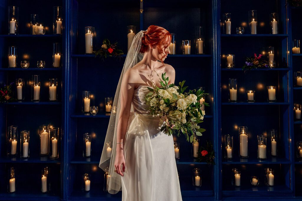 red head bride with veil in front of candle lit room