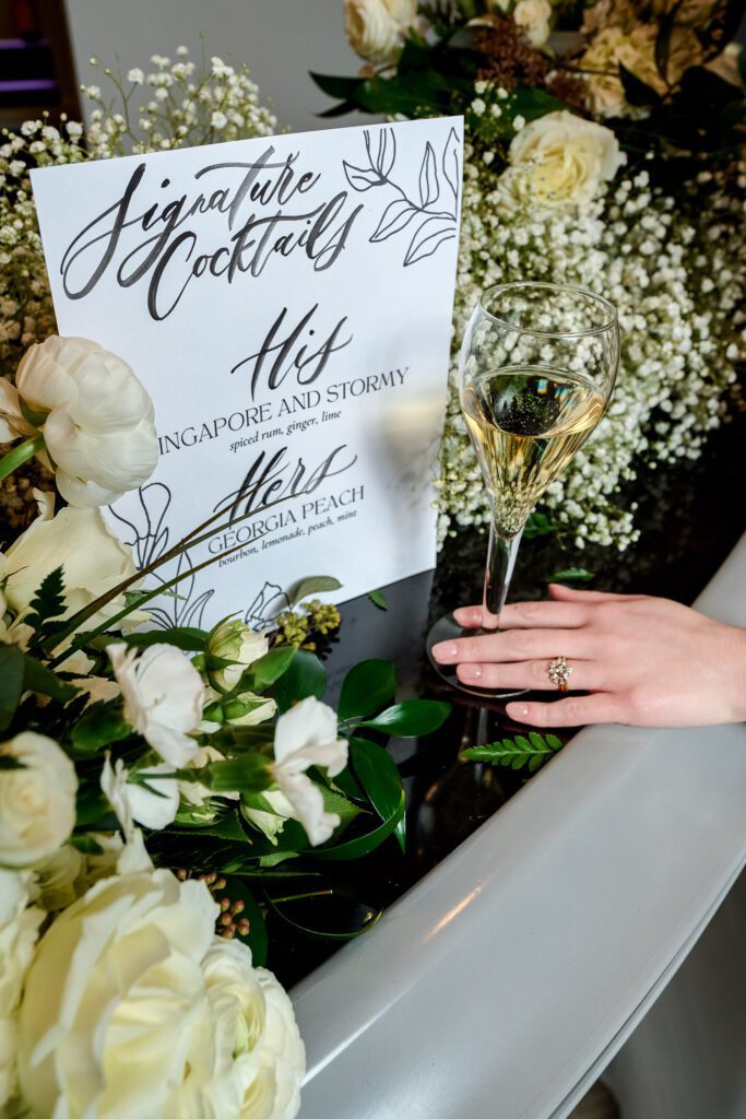 calligraphy menu with roses and baby breath with brides hand and champagne glass