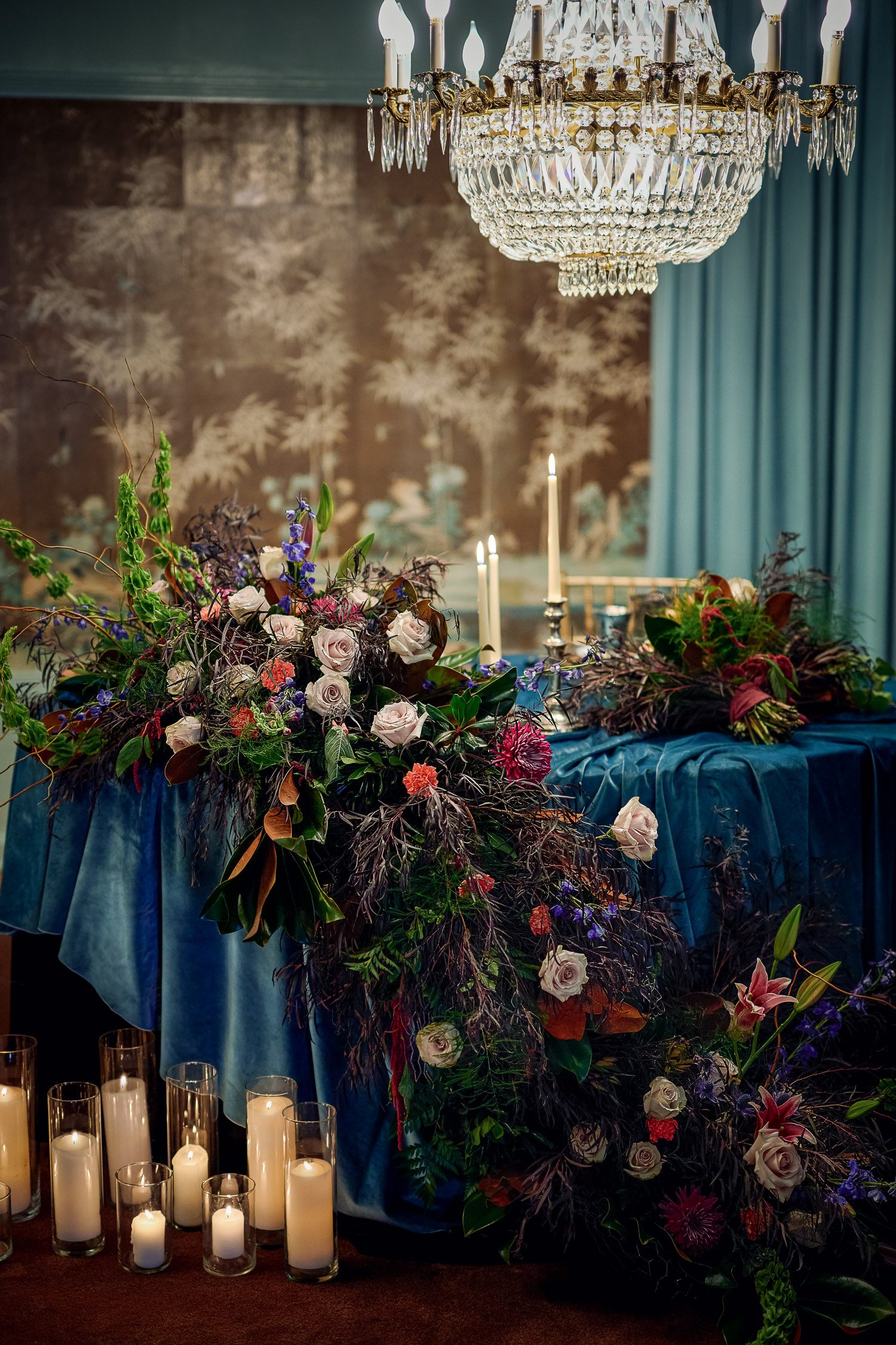 Blue Velvet Table Cloth with flowers cascading over edge with hand painted wall paper at Chatol in Centralia, Missouri.