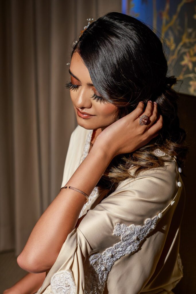 bride touching hair wearing Betz Jewelers oval pink ring in silk robe