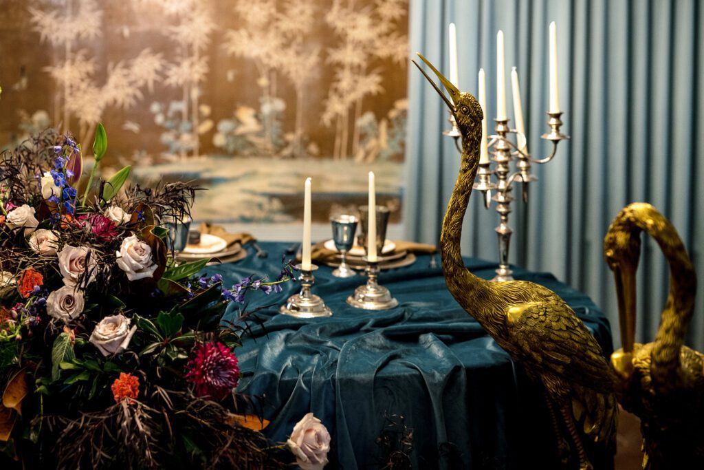 velvet table with gold cranes and dark moody flower spray