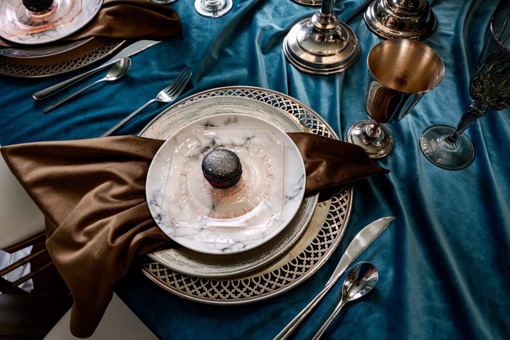 glitter dusted black macaroon on moody place setting on blue velvet