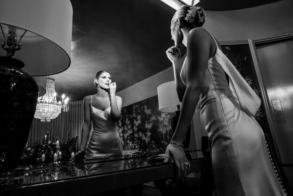 black and white photo of bride touching up lipstick