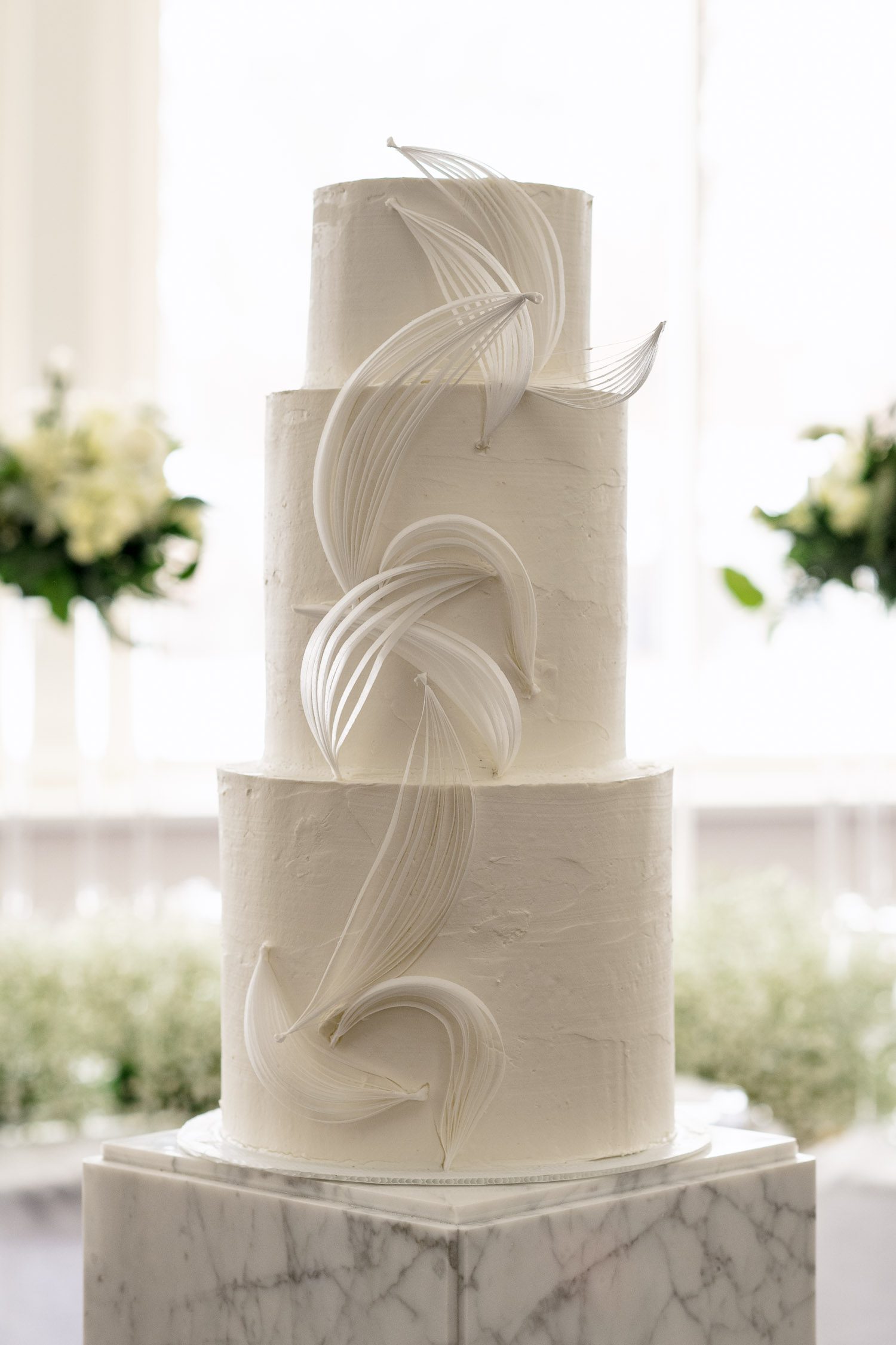 white three tiered wedding cake with architectural flourishment