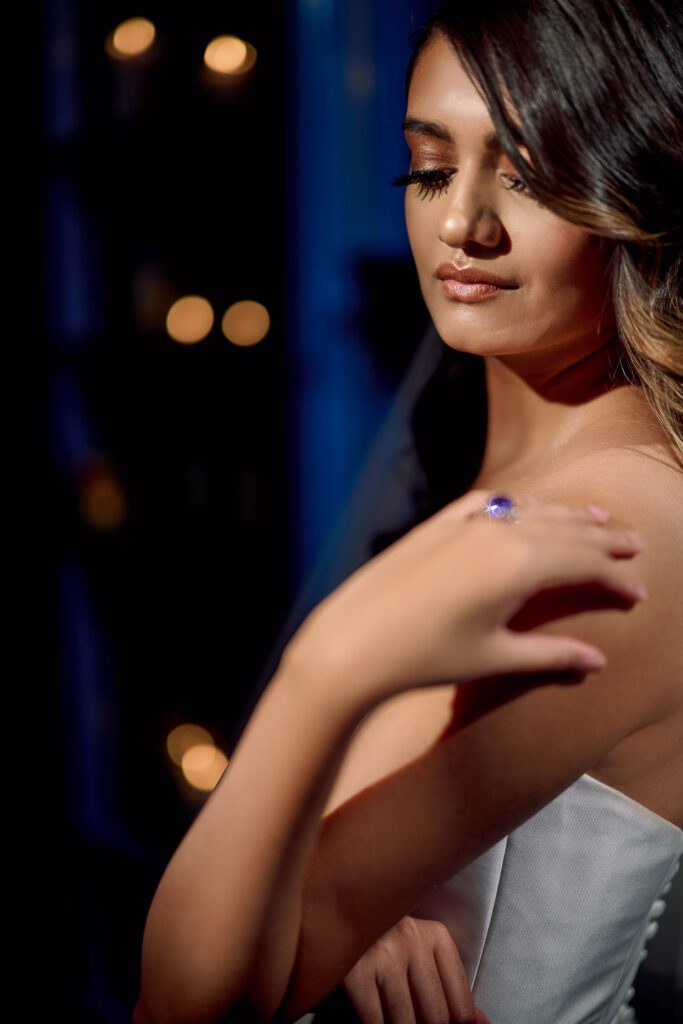 bride with sapphire ring in front of candle lit wall