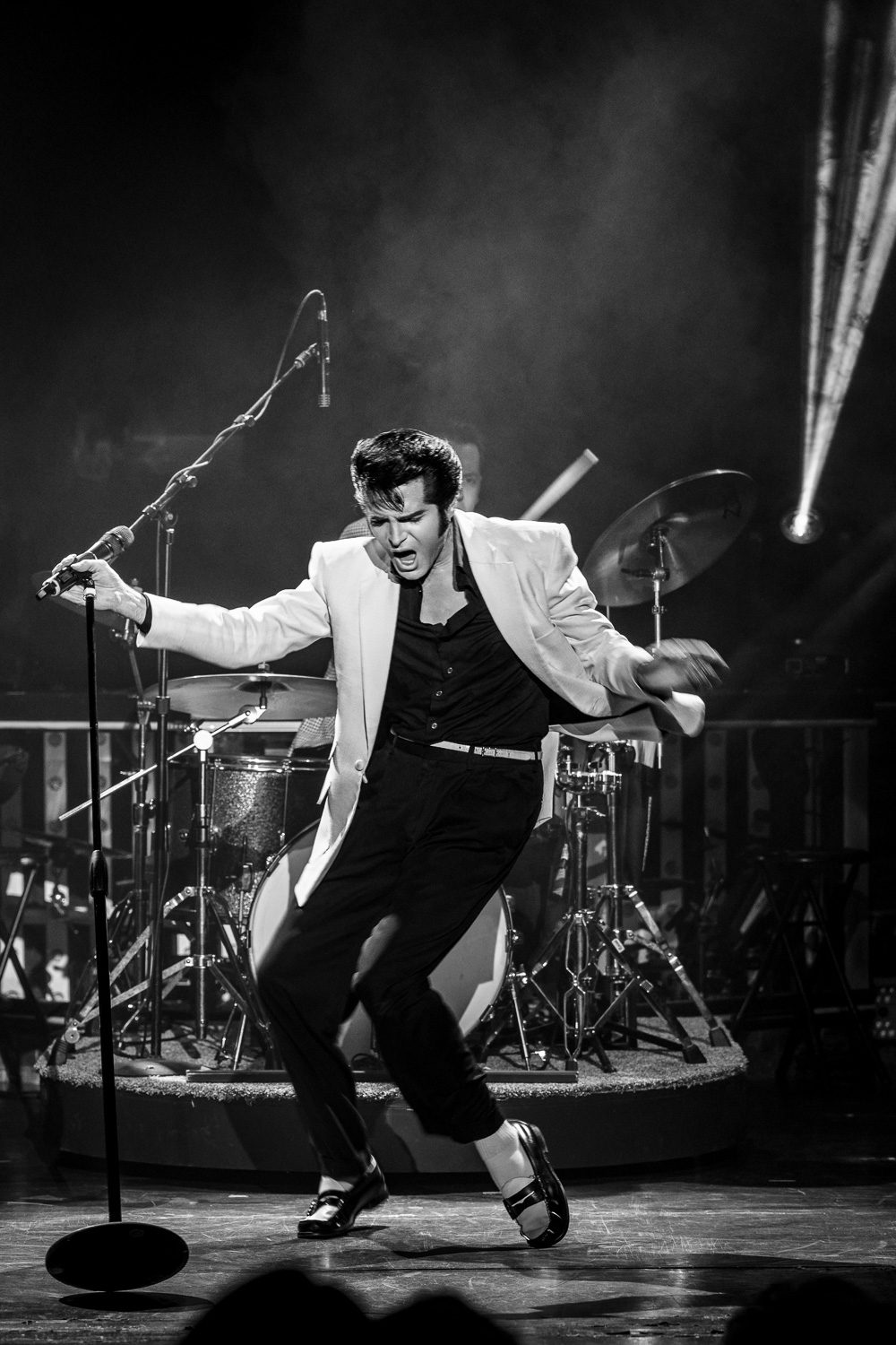 Black and white image of Dean Z dancing on his toes as Elvis Presley with penny loafers and a light colored blazer.