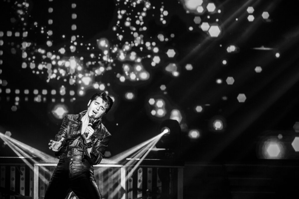 Black and white photo of Dean Z singing passionately as Elvis Presley in black leather in Branson, Missouri.