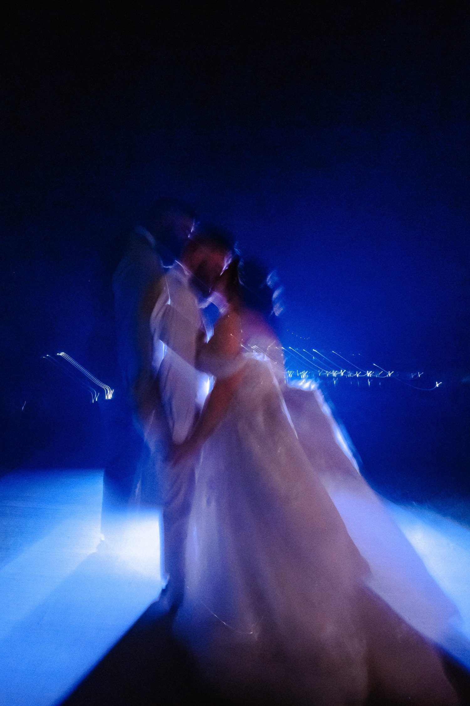 Blurry photo with blue colors and bride and groom kissing