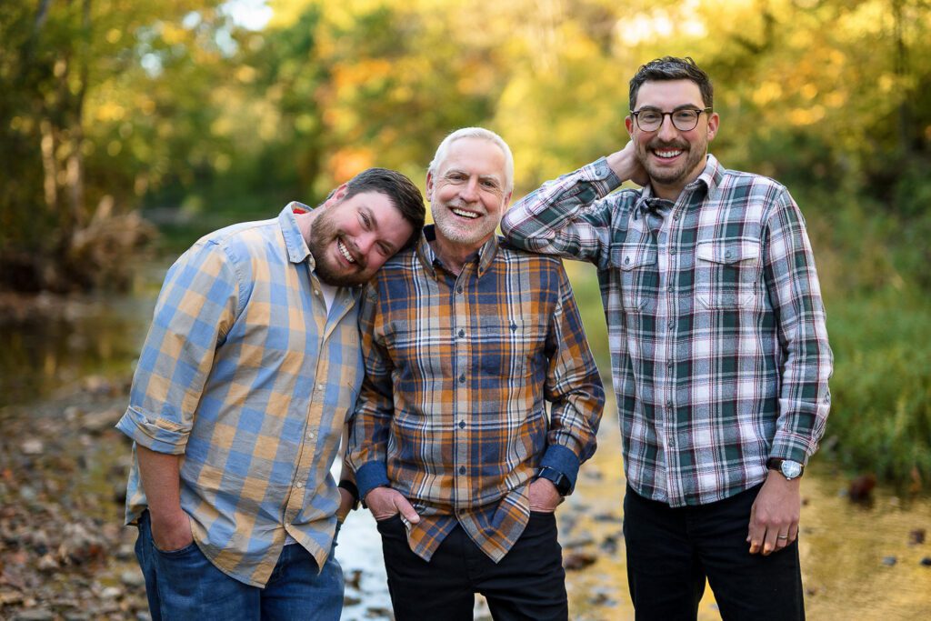 father and sons pose together with fall leaves