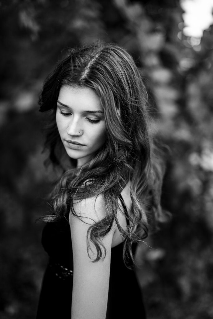 senior girl with long hair looks down shoulder