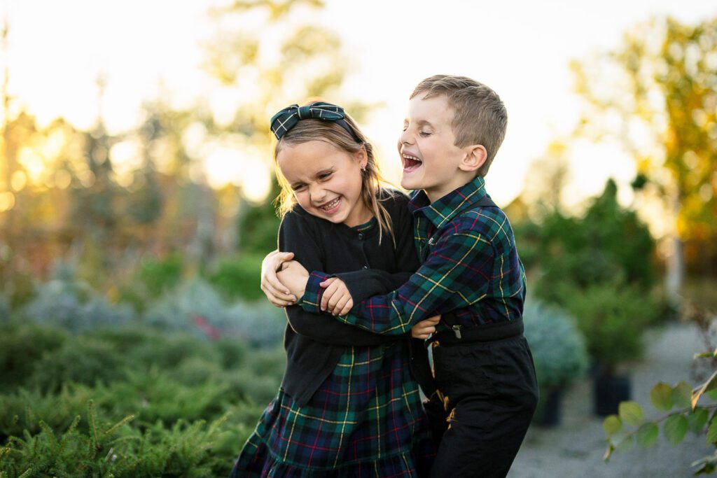 two small children wearing green plaid laugh and hug