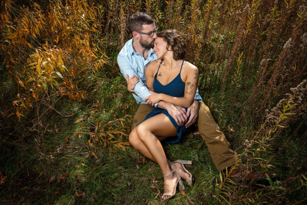 girl lays in fiance's lap as he kisses her head during engagement photos