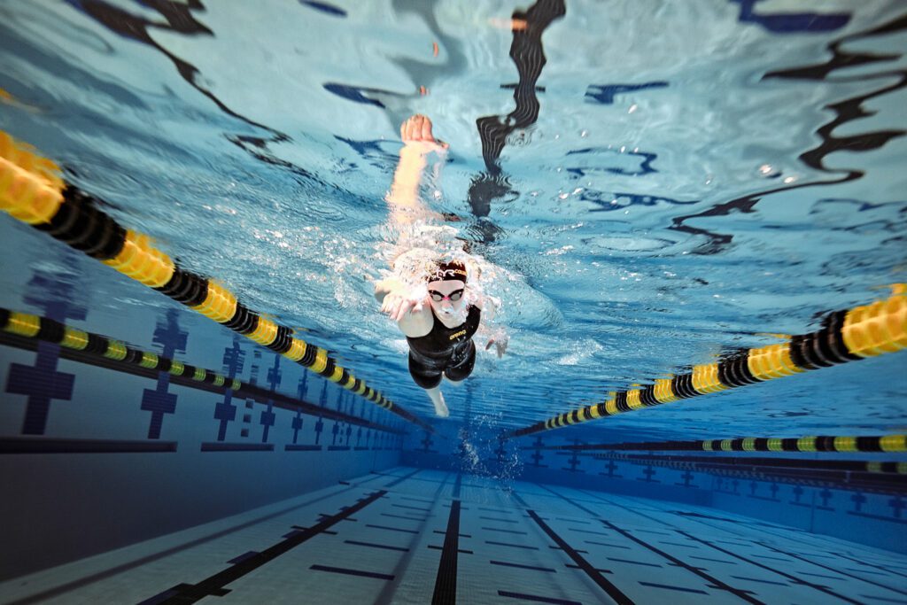 Female swimmer underwater with black and gold lane floats in mizzou aquatic center