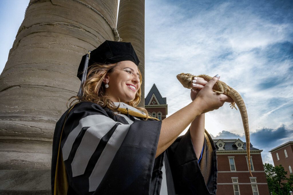 Mizzou senior girl holding bearded dragon lizard at mu columns