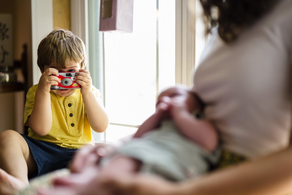 young child takes photo of newborn brother