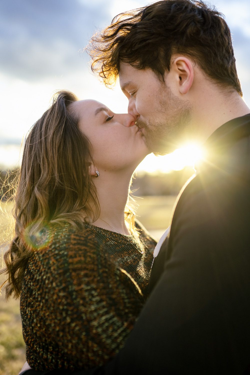 Couple kiss as the sun peaks through on cold day